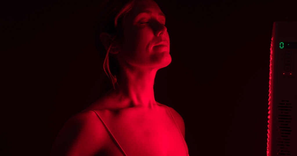 Woman getting red light therapy in a beauty salon. Mature woman getting anti-aging treatment from a red light device. Skin care and rejuvenation procedure.