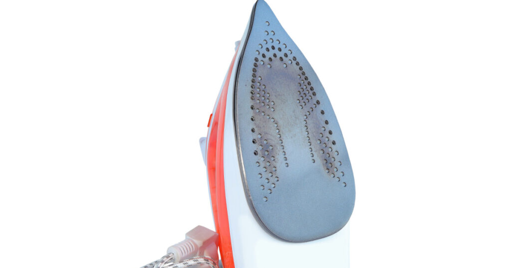 Burnt dirty electric flat iron. Old iron on white background with clipping path. burnt iron for ironing. used dirty iron not suitable for ironing.