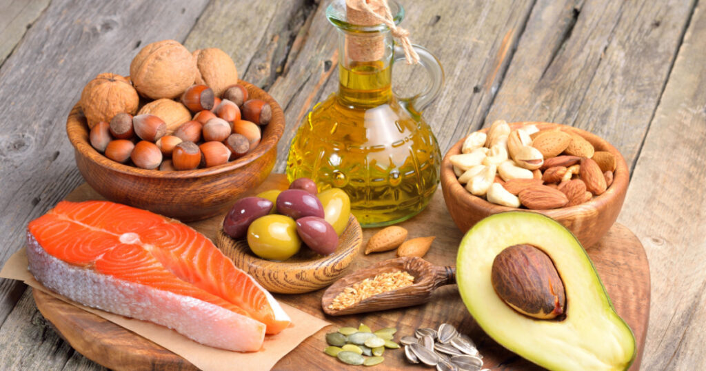Selection of healthy fat sources on wooden background.