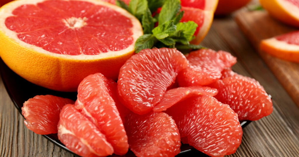 Juicy grapefruit pieces with fresh mint in a bowl, close up