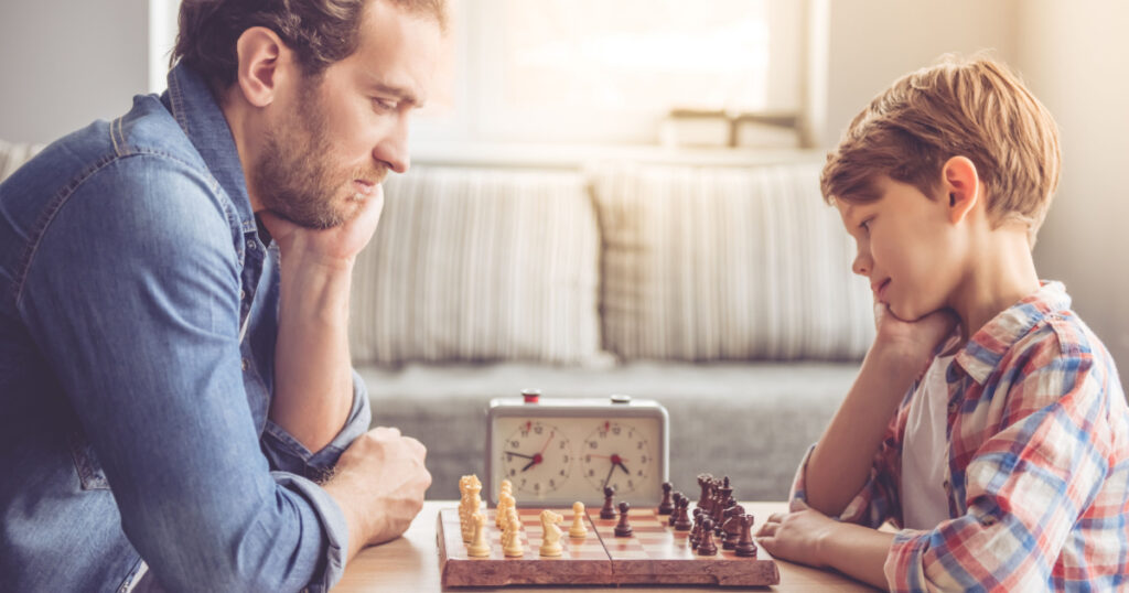 Father and son are playing chess while spending time together at home