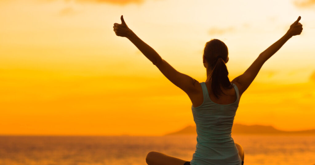 Healthy woman celebrating during a beautiful sunset. Happy and Free.
