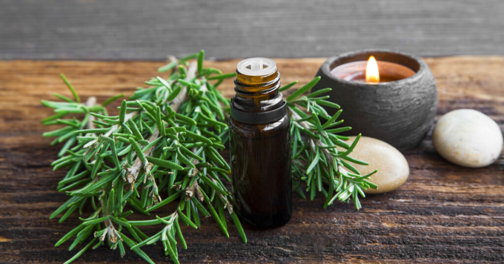 Rosemary aromatherapy oil with rosemary herb on wooden background with candle