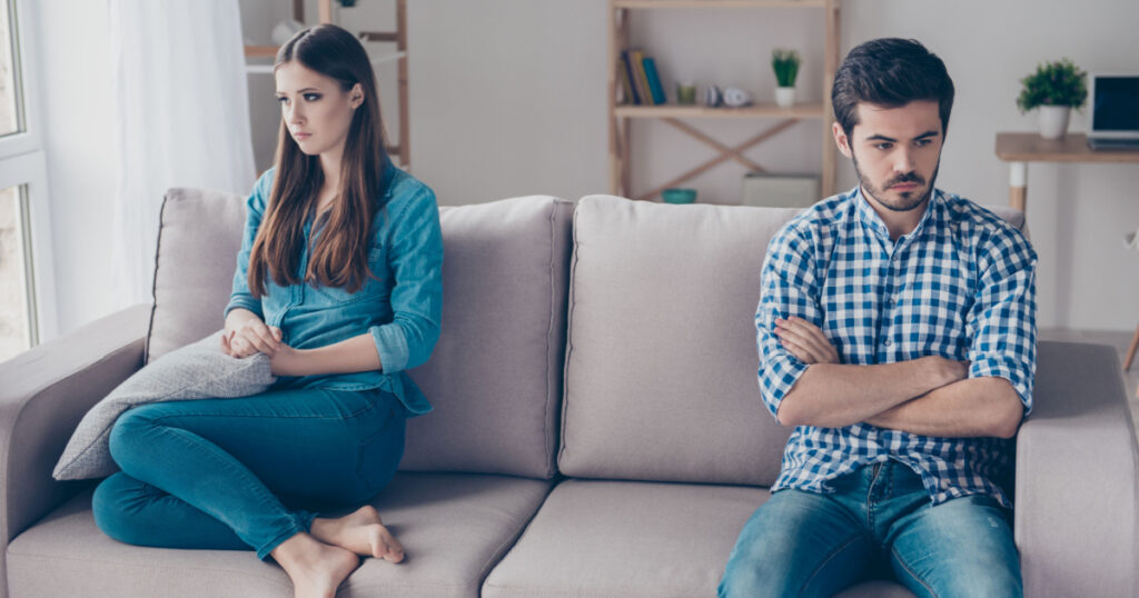 I am not talking to you! Mistrust and cheat problems. Annoyed couple is ignoring each other, sitting on the couch indoors at home with sad faces