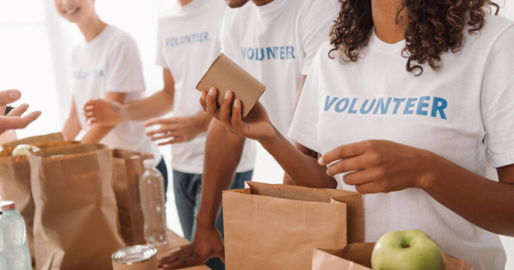 cropped shot of young volunteers group packing food and drinks for charity