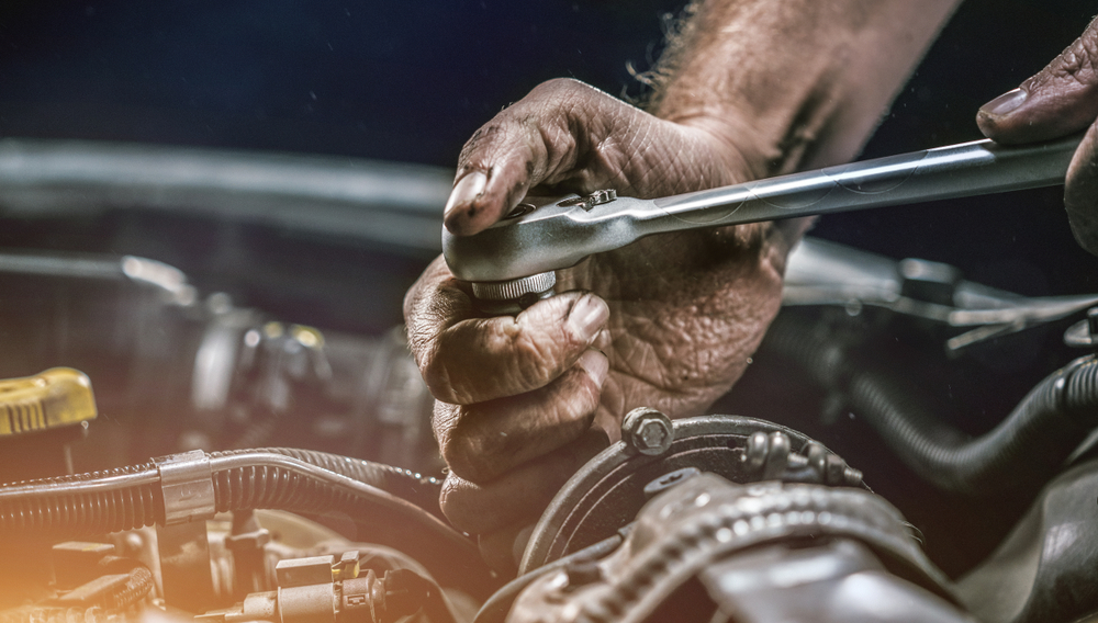Auto mechanic working on car engine in mechanics garage. Repair service. authentic close-up shot