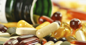 bottle with various pills, softgels, and tablets spilling out of it. Dietary supplement concept
