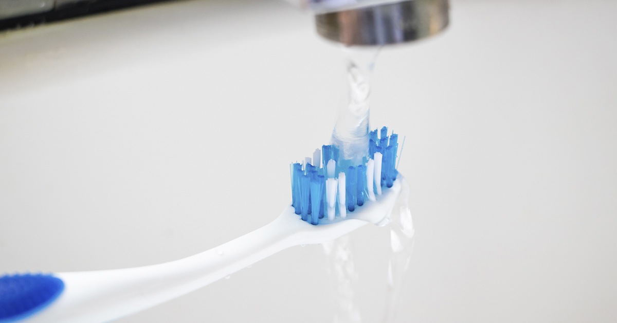 tooth brush held under tap running water