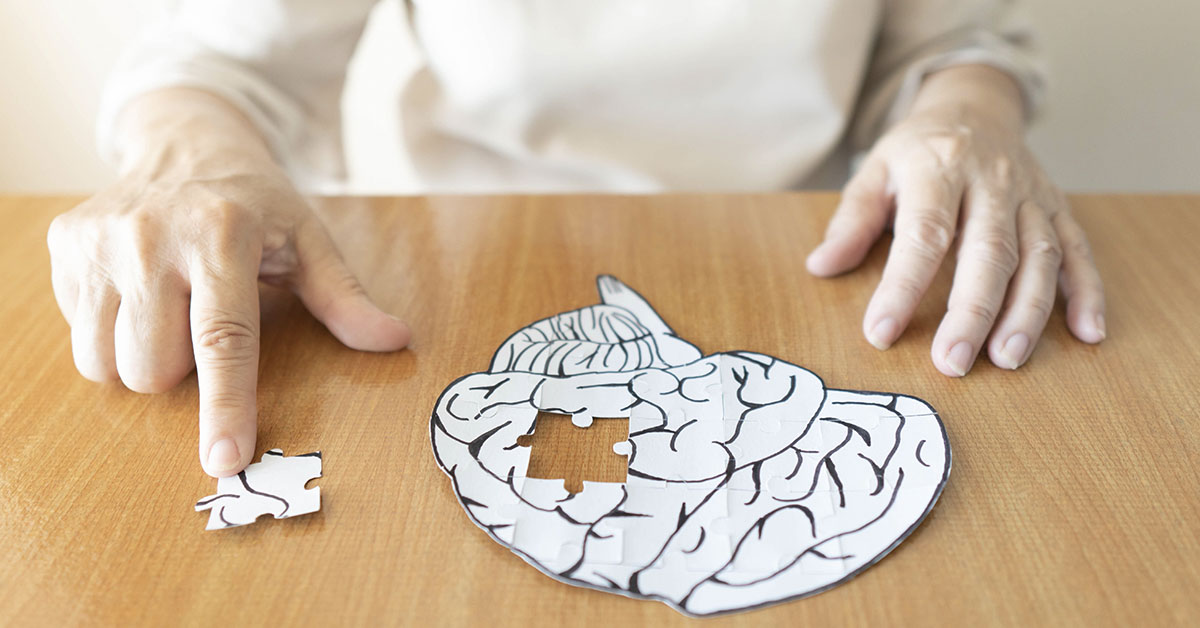 person putting together puzzle of human brain. Alzheimer's dementia concept