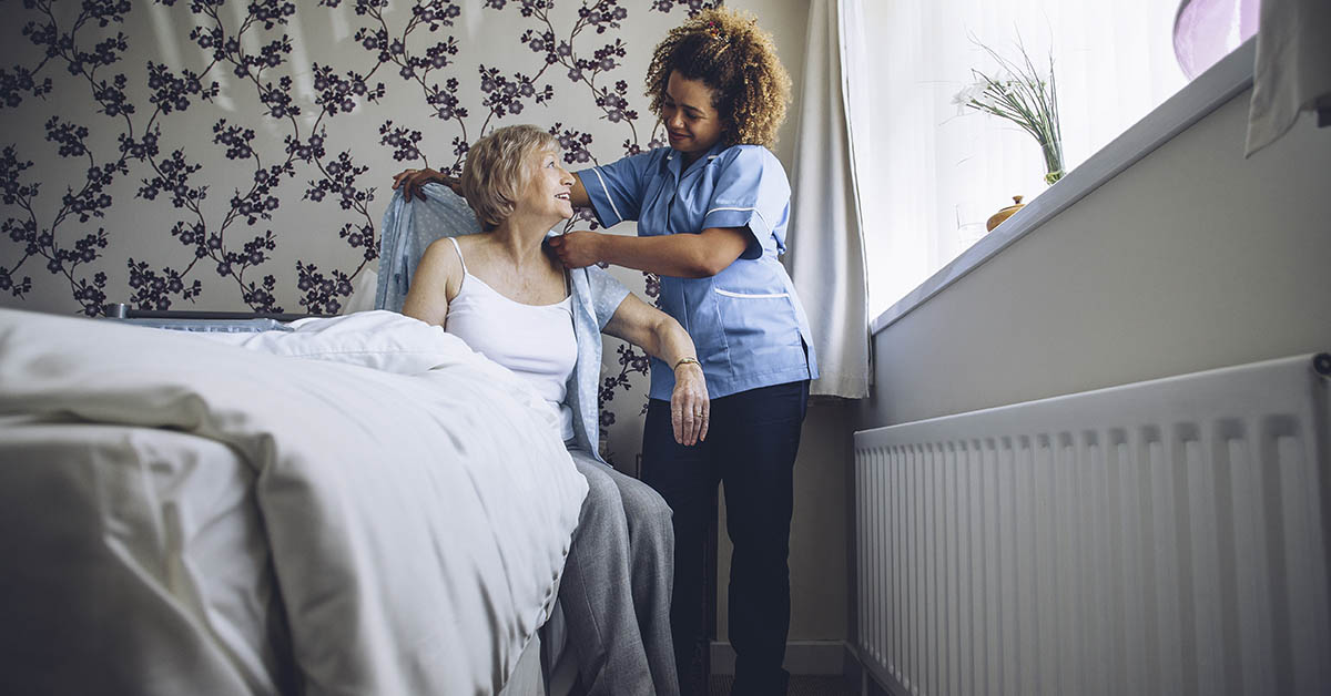 woman helping elderly woman out of bed