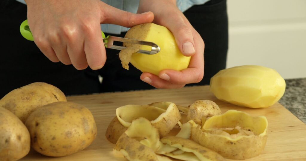 Preparing dinner: hands peeling potatoes for boiling
