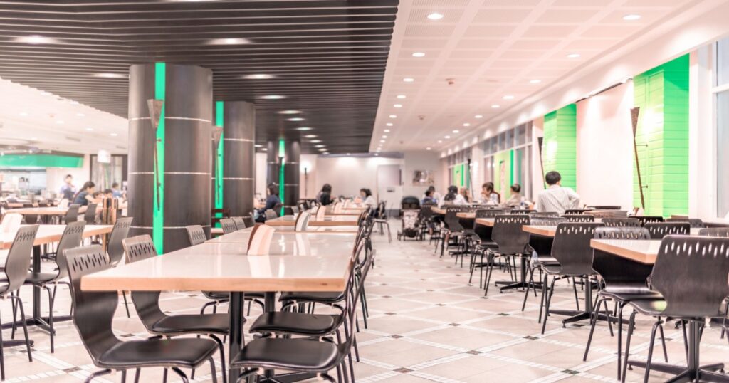 Modern interior of cafeteria or canteen with chairs and tables, eating room in selective focus