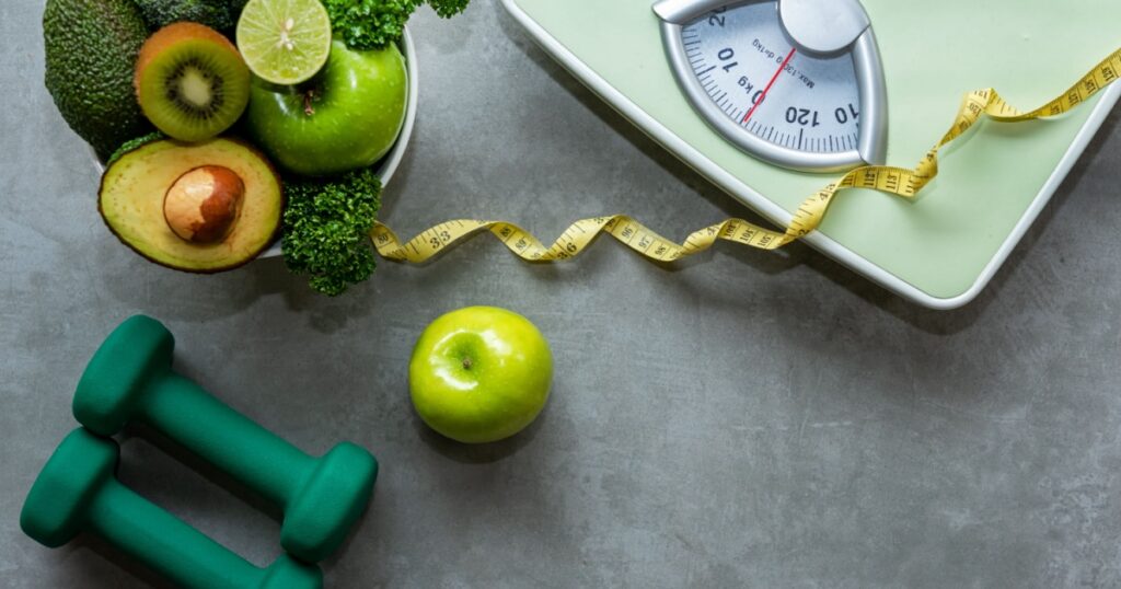 Diet and Healthy life loss weight slim Concept. Organic Green apple and Weight scale measure tap with nutrition vegan vegetable and sport equipment gym for body women diet fit. Top view copy space.