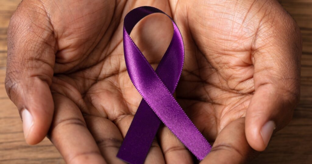 Close-up Of A Person's Hand Holding Ribbon To Support Alzheimer's Disease Awareness