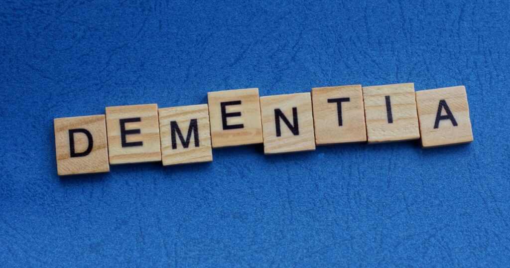 word dementia made from brown wooden letters lies on a blue table