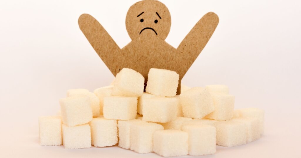 Sugar addiction, insulin resistance, unhealthy diet, figure of a cardboard man surrounded by refined sugar cubes on white background, diabetes protection medical concept