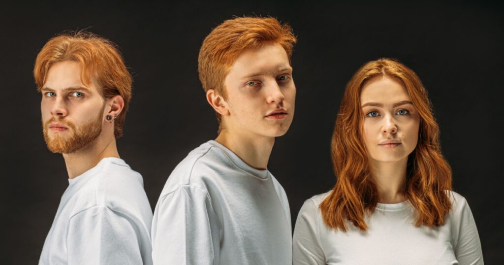 group of young, attractive caucasian people with natural red hair gathered together in studio with black background.redhead day. rare type of people with natural red hair. people diversity