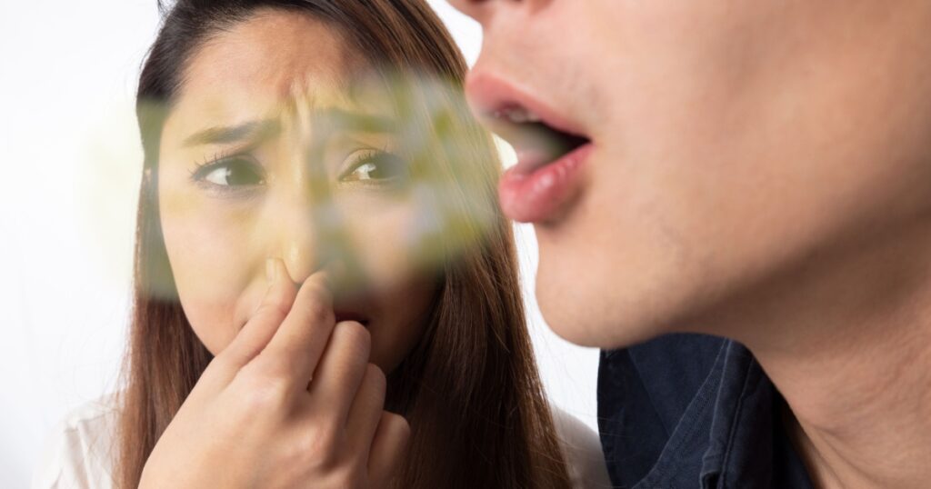 A woman pinching her nose due to bad breath in a man.