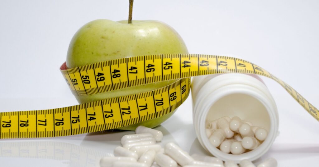 Apple with measuring tape and pills