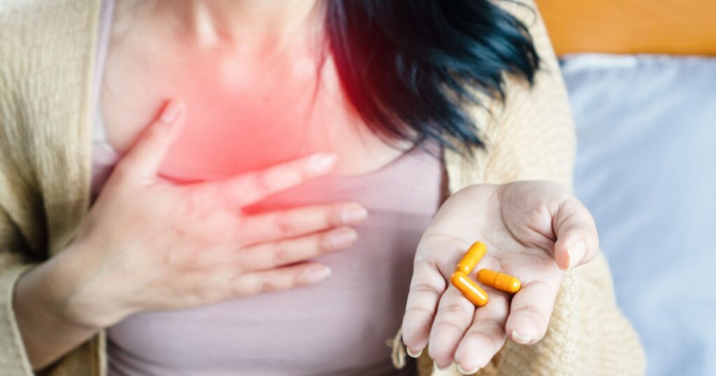 woman taking turmeric pill, or curcumin herb medicine for GERD, treatment for heartburn from acid reflux disease
