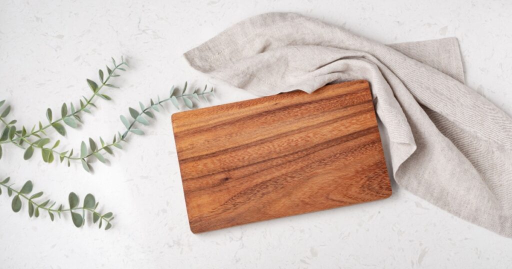 Wood cutting board with napkin on marble table, top view