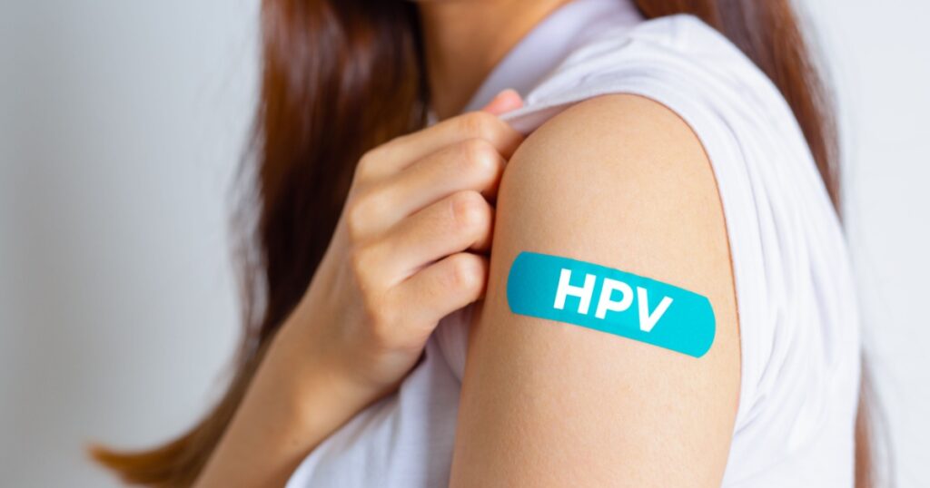 HPV (Human Papillomavirus) Teenager woman showing off an blue bandage after receiving the HPV vaccine.viruses Some strains infect genitals and can cause cervical cancer. Woman health concept.