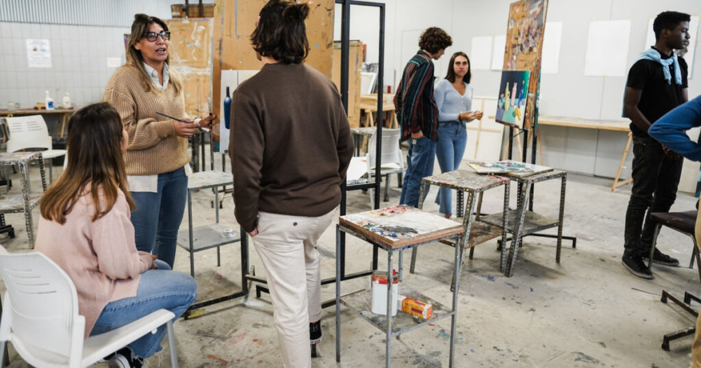Mature teacher working with art students during painting class at school - Focus on woman face