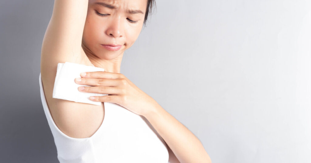 A young woman who wipes the gums under her armpits under concern. Hyperhidrosis