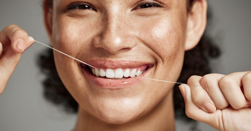 Woman portrait, dental floss and flossing teeth with smile for oral hygiene, health and wellness on studio background. Face of female happy about self care, healthcare and grooming for healthy mouth