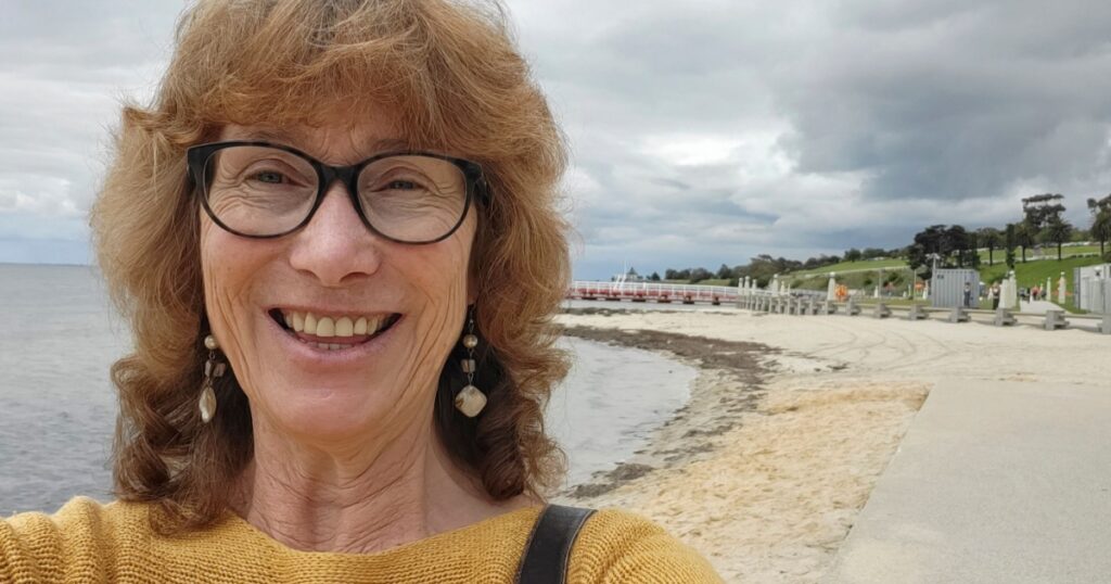 Mature woman takes a Selfie while walking along Geelong promenade. Geelong is a popular tourist destination in Victoria state with safe beaches and restaurants.