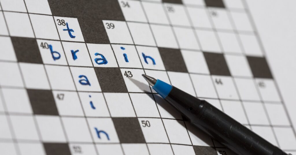 A crossword puzzle saying train and brain. An image of a pencil against an empty crossword puzzle. Crossword puzzles are excellent training for brains.