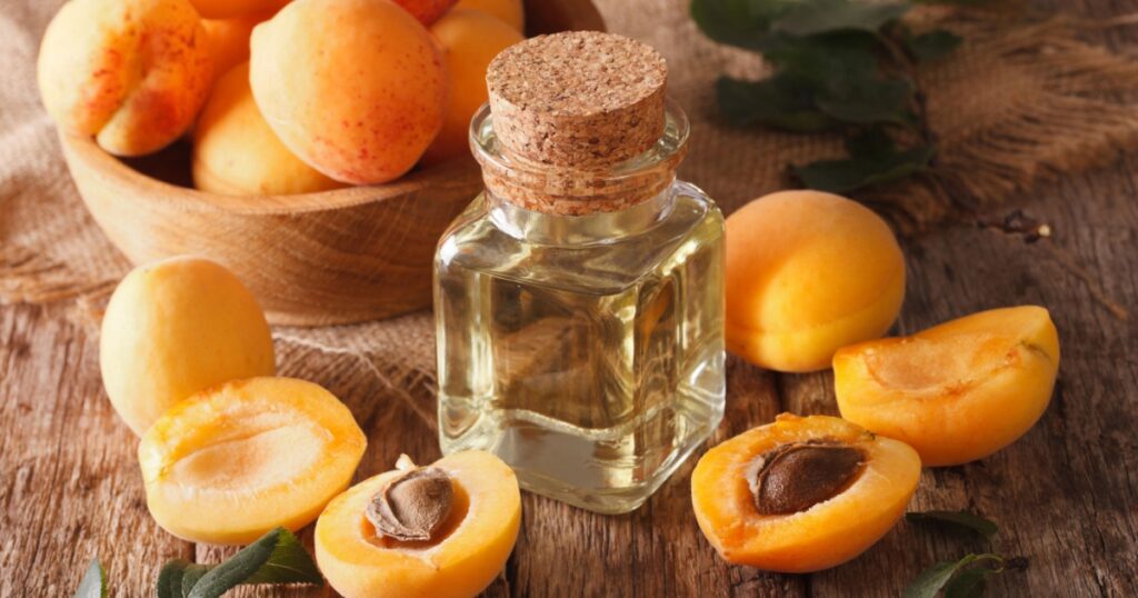 apricot kernel oil in a glass jar closeup on the table and ingredients. Horizontal