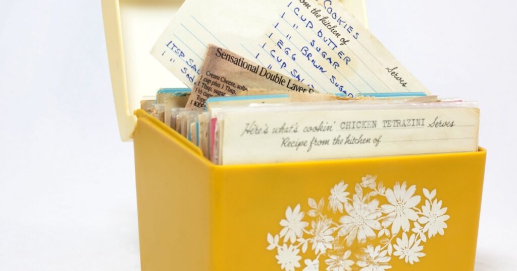 Old, yellow 1960s recipe box with handwritten recipes on index cards