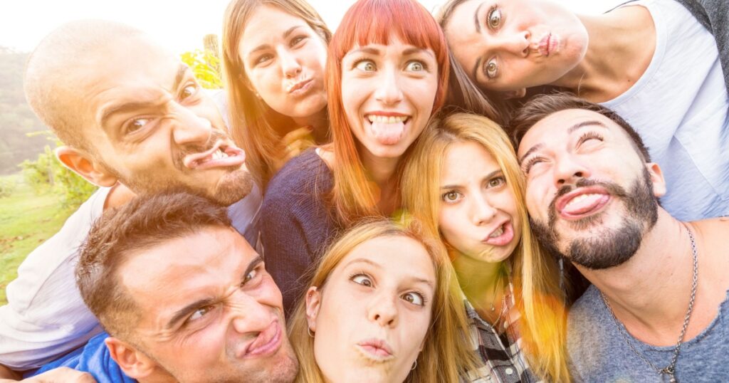 Best friends taking selfie outdoor with back lighting - Happy youth concept with young people having fun together - Cheer and friendship at picnic - Warm vivid filter with focus on redhead woman
