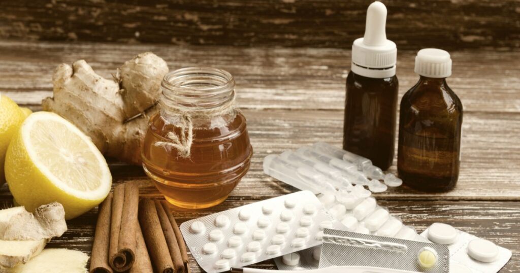 Ginger, lemon, honey and different drugs with thermometer on wooden background.Alternative remedies and traditional pills to treat colds and flu. Natural medicine vs conventional medicine concept