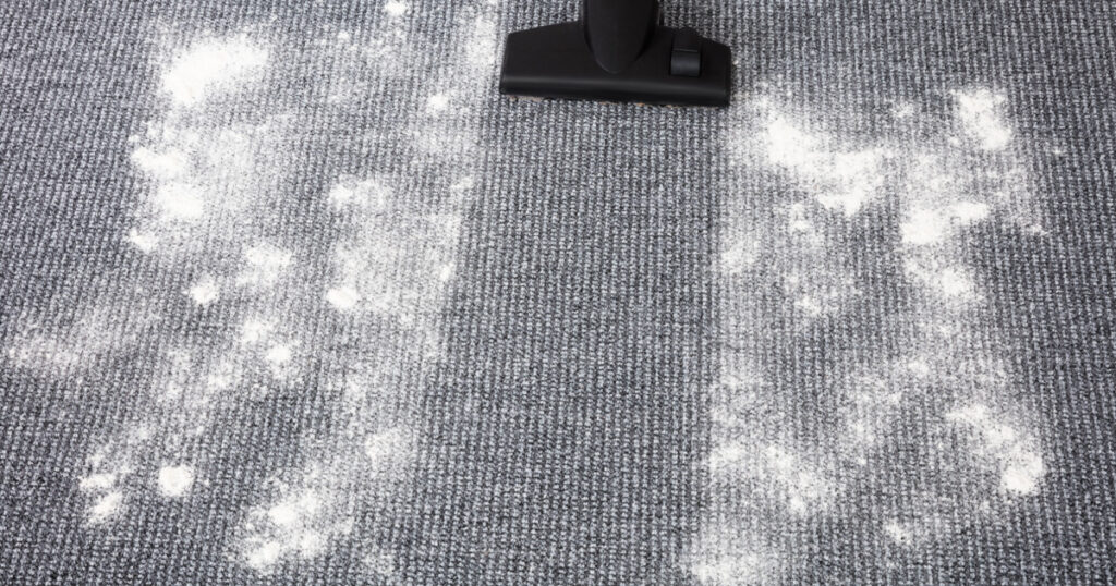 Close-up Of Vacuum Cleaner Cleaning Dirt On Carpet