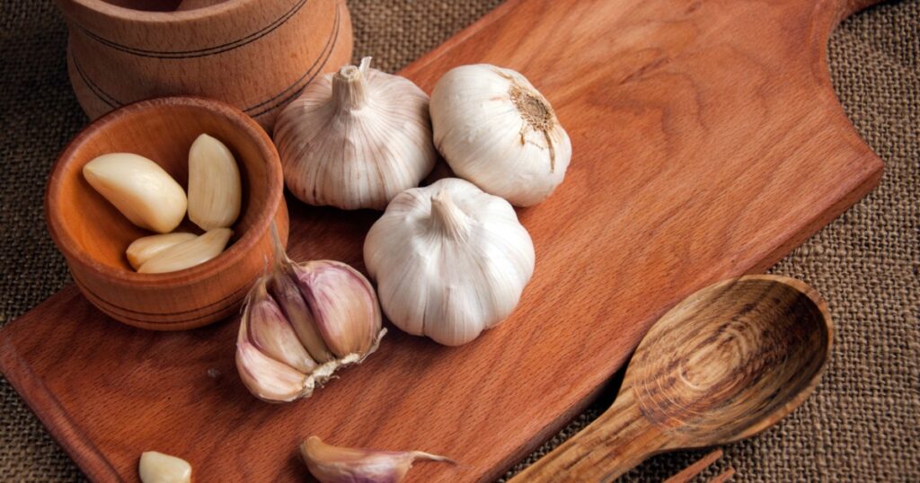 Garlic. sliced garlic, garlic clove, garlic bulb in wooden bowl place on chopping block on vintage wooden background. Place for text, copy space Concept of healthy food. Top view
