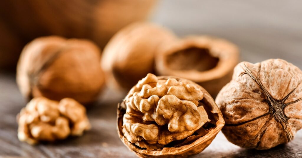 Walnuts kernels on dark desk with color background, Whole walnut in wood vintage bowl.