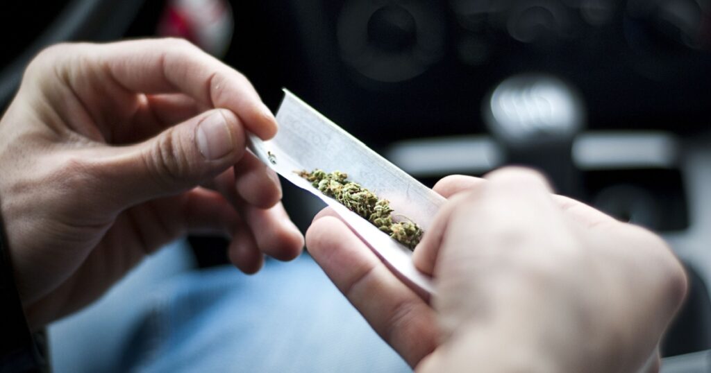 man making joint and a stash of marijuana narcotics in the car