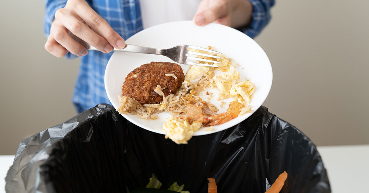 person scraping foot off of plate into garbage