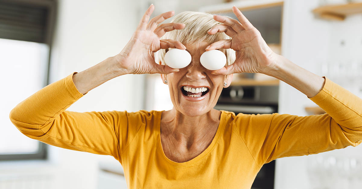 elderly woman with eggs placed over her eyes. Egg health benefit concept
