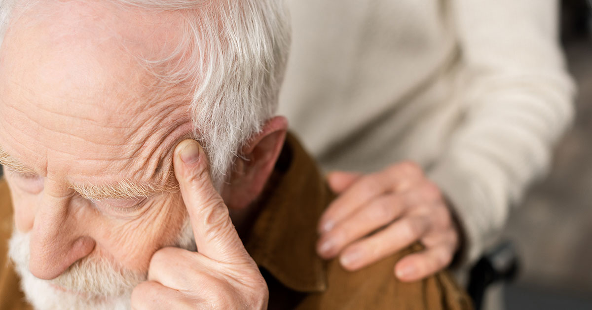 elderly man with hand placed on shoulder being comforted.