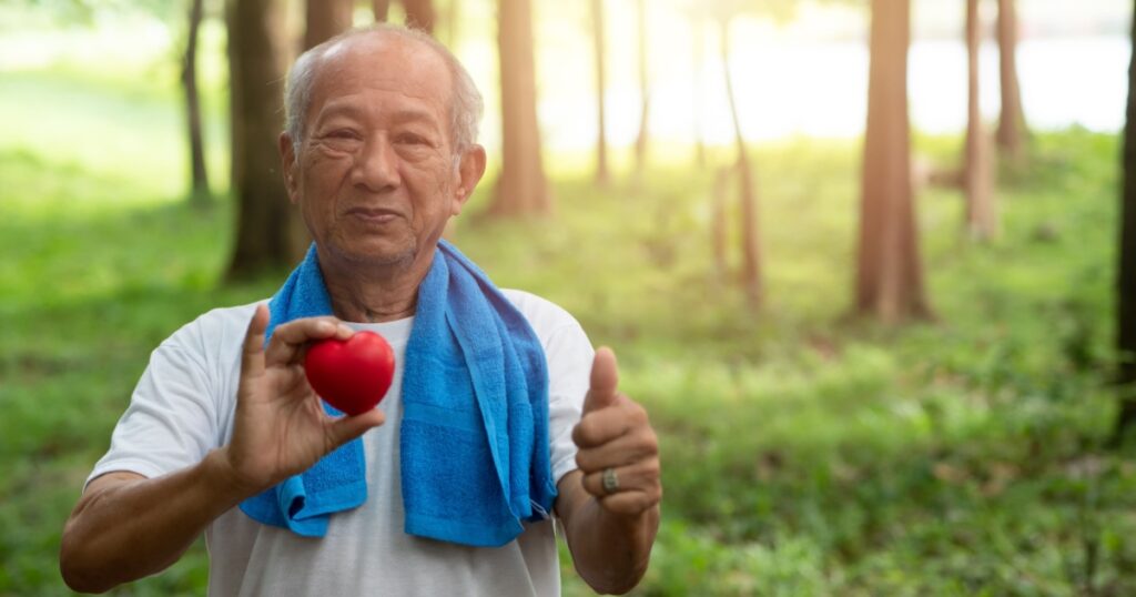 Male senior holding red heart and Happy smile. Health care, Healthy with exercise and Healthy good start, insurance, world heart day