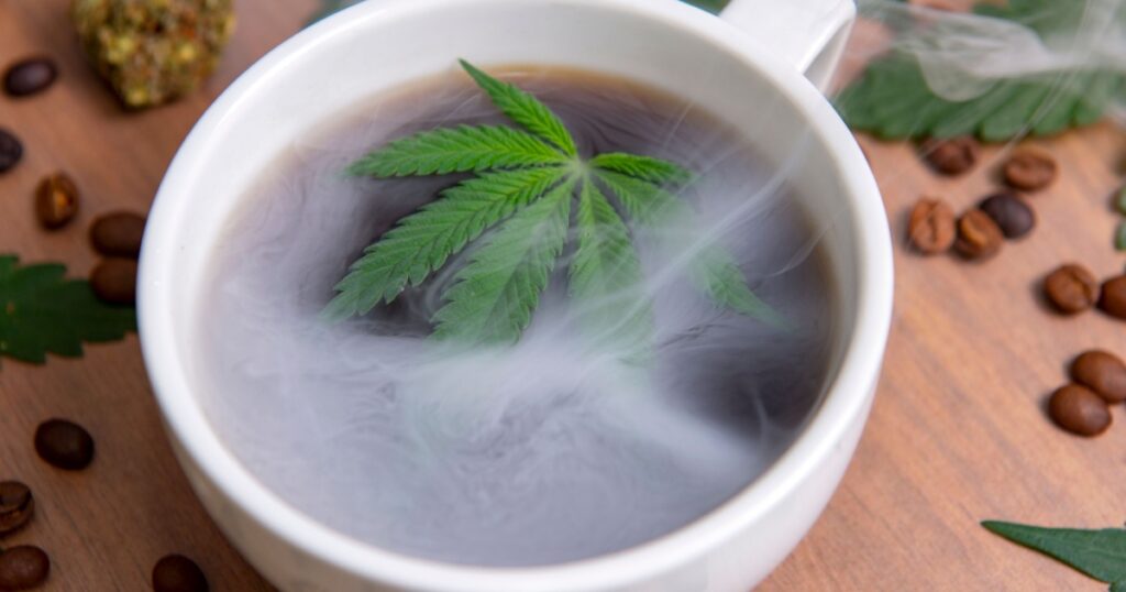 Detail of smoky cannabis coffee cup with beans, nugs and marijuana leaves, marijuana edibles concept