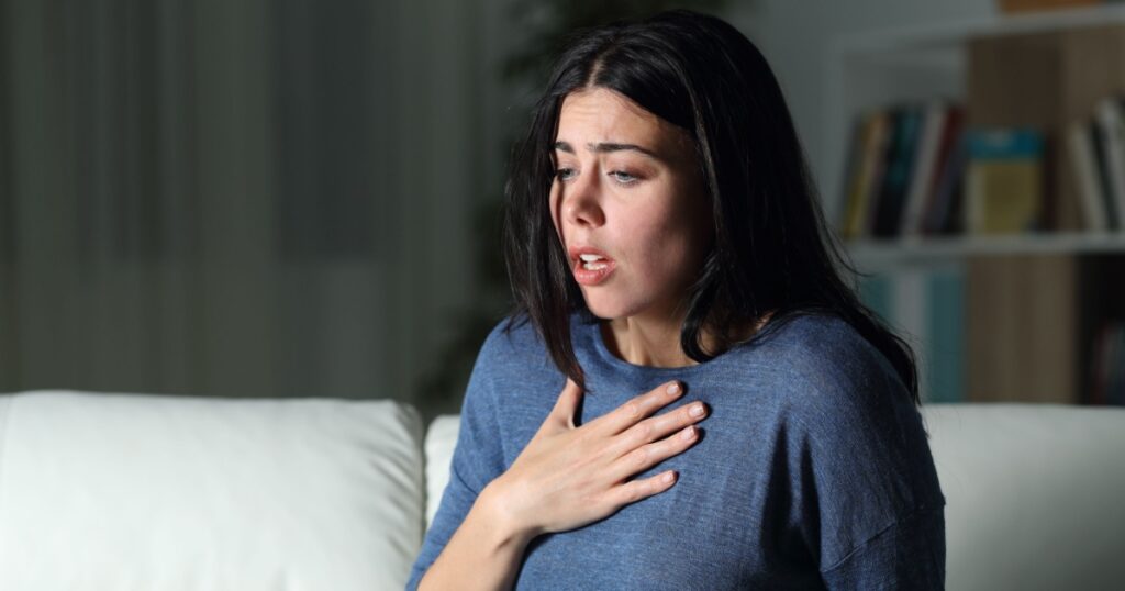 Woman suffering an anxiety attack alone in the night on a couch at home
