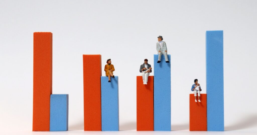 Miniature people sitting on a bar graph. The concept of declining birth rate and aging population.