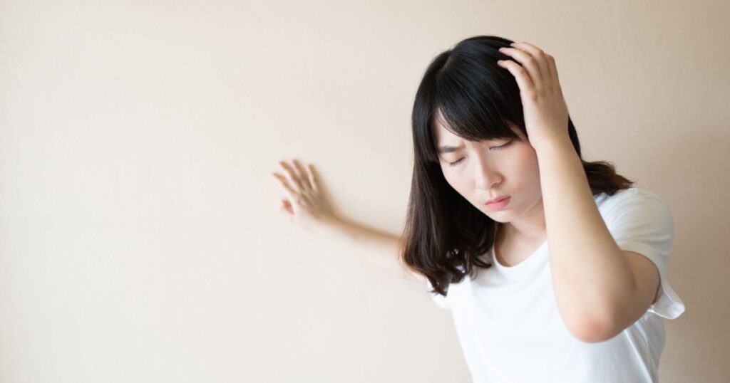 Young asian female suffering from dizziness, vertigo and headache over white background. Cause of dizzy inclued migraine, stress, stroke, BPPV, Meniere’s disease or brain tumor. Health care problem.