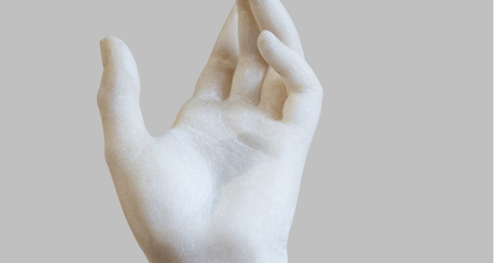 side view closeup of white stone marble statue hand reaching out to the heavens isolated on grey background