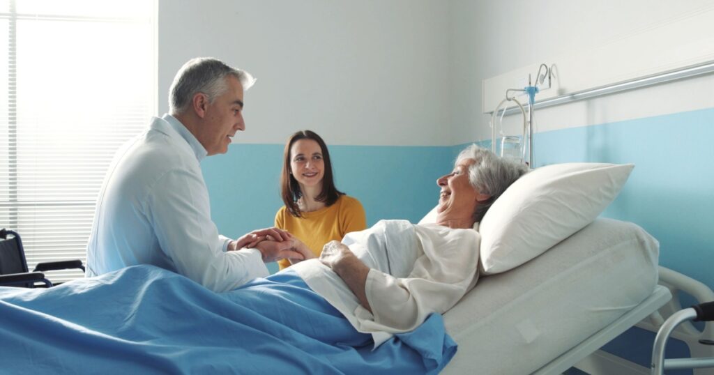 Professional friendly doctor meeting a senior patient on a hospital bed and her daughter, senior care concept