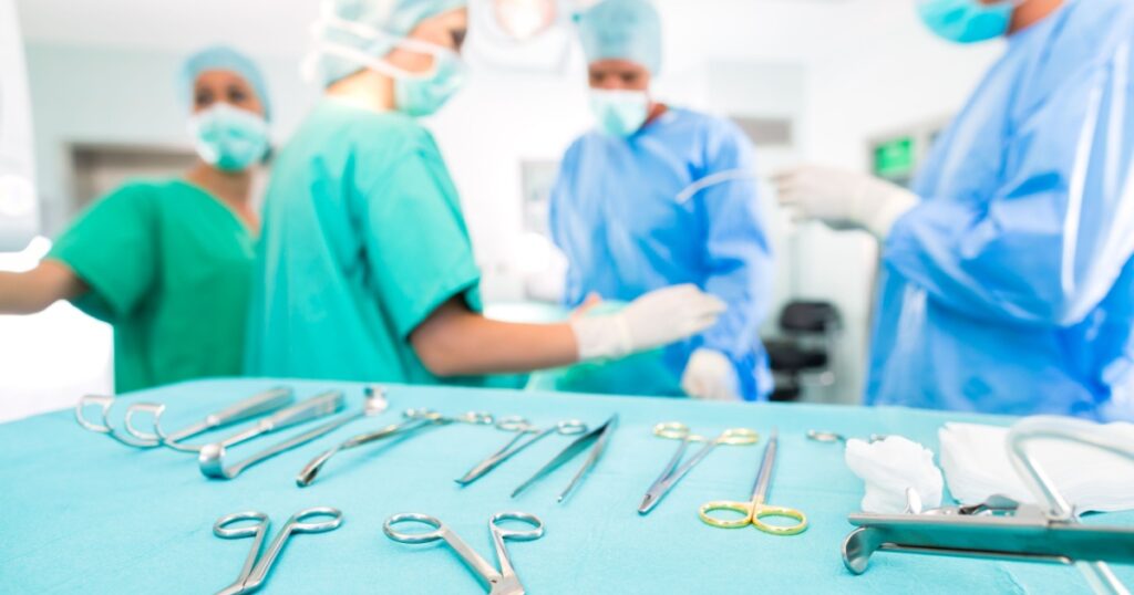 Hospital - surgery team in the operating room or Op of a clinic operating on a patient, perhaps it's an emergency a assistant holding a cotton swap forceps